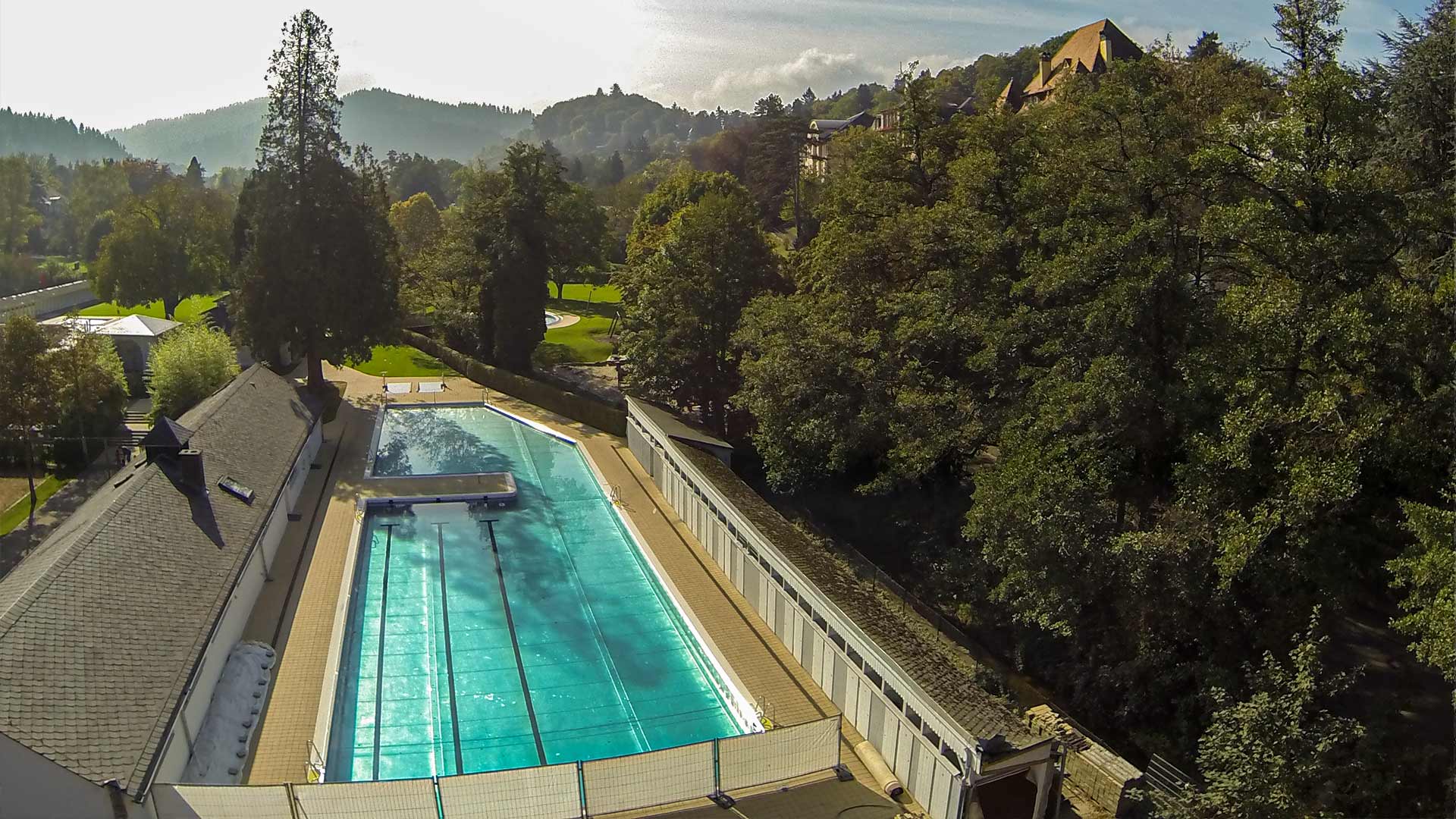 Ansicht auf einen Swimmingpool vor einer Grünanlage mit Bergen