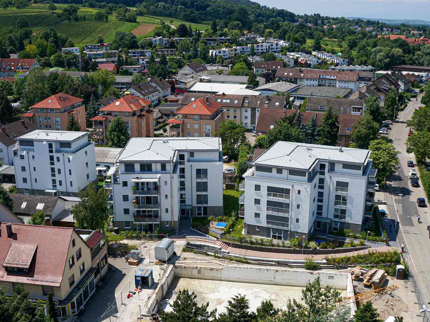 Vogelperspektive auf ein Neubau-Wohngebäude in Stadt vor Berg