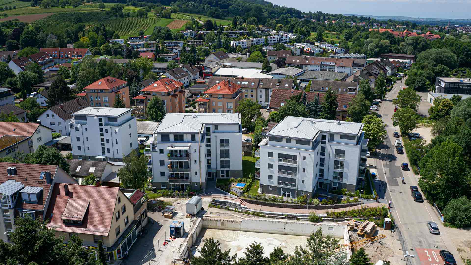 Vogelperspektive auf ein Neubau-Wohngebäude in Stadt vor Berg