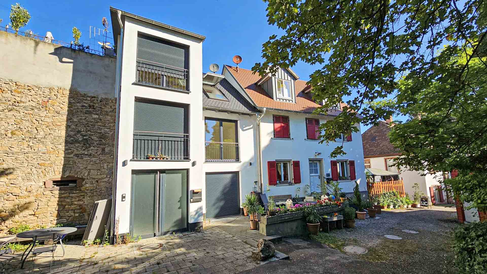 Ansicht auf ein weisses Gebäude an einer Steinmauer mit Innenhof