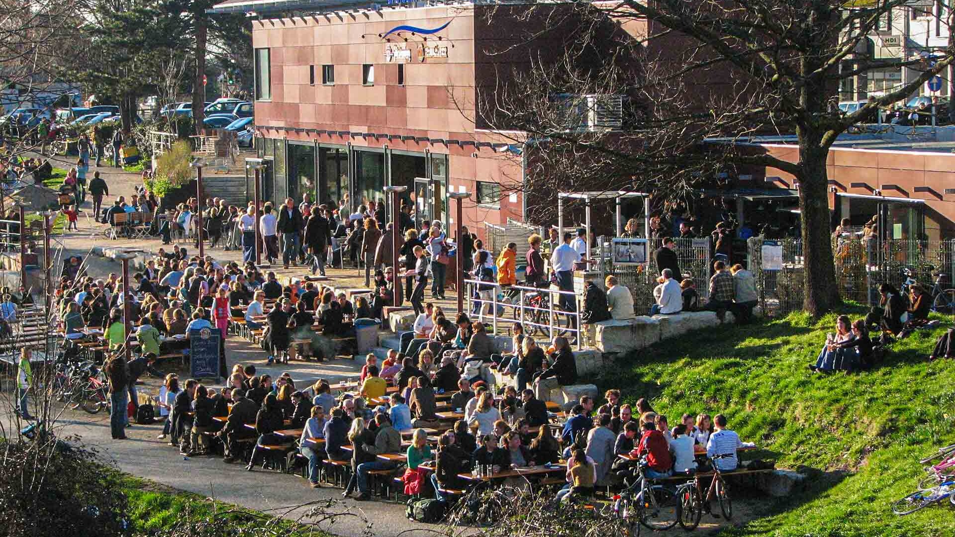Viele Menschen an Tischen in einem gastronomischen Außenbereich