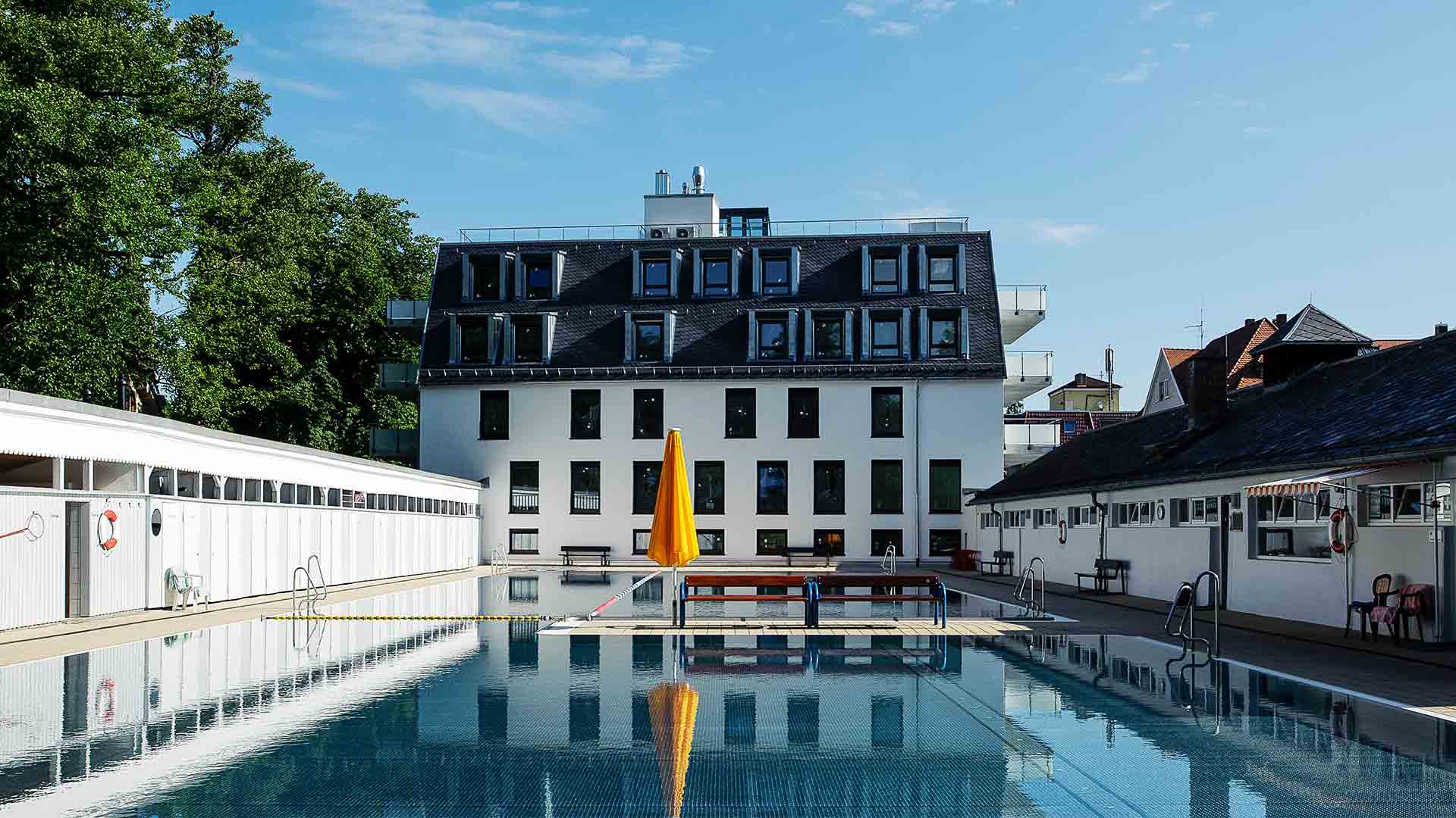 Ansicht auf ein saniertes weisses Gebäude vor einem Schwimmbad-pool