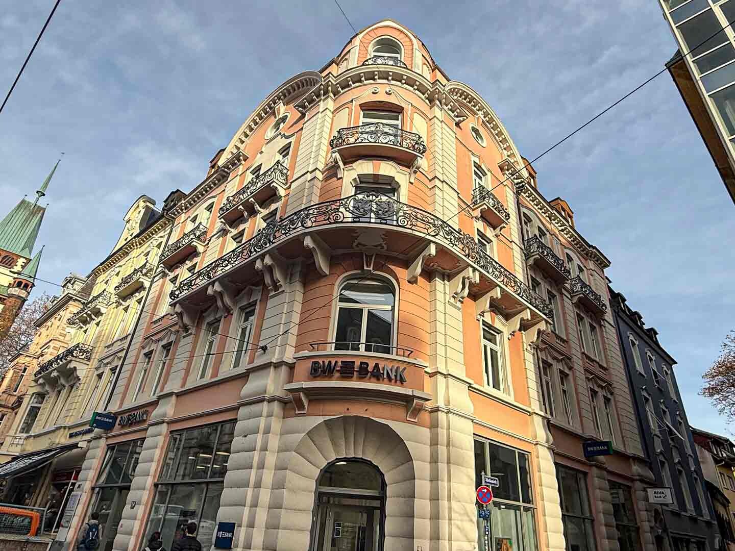 Frontalansicht auf ein historisches saniertes Gebäude mit rosa Wandfarbe