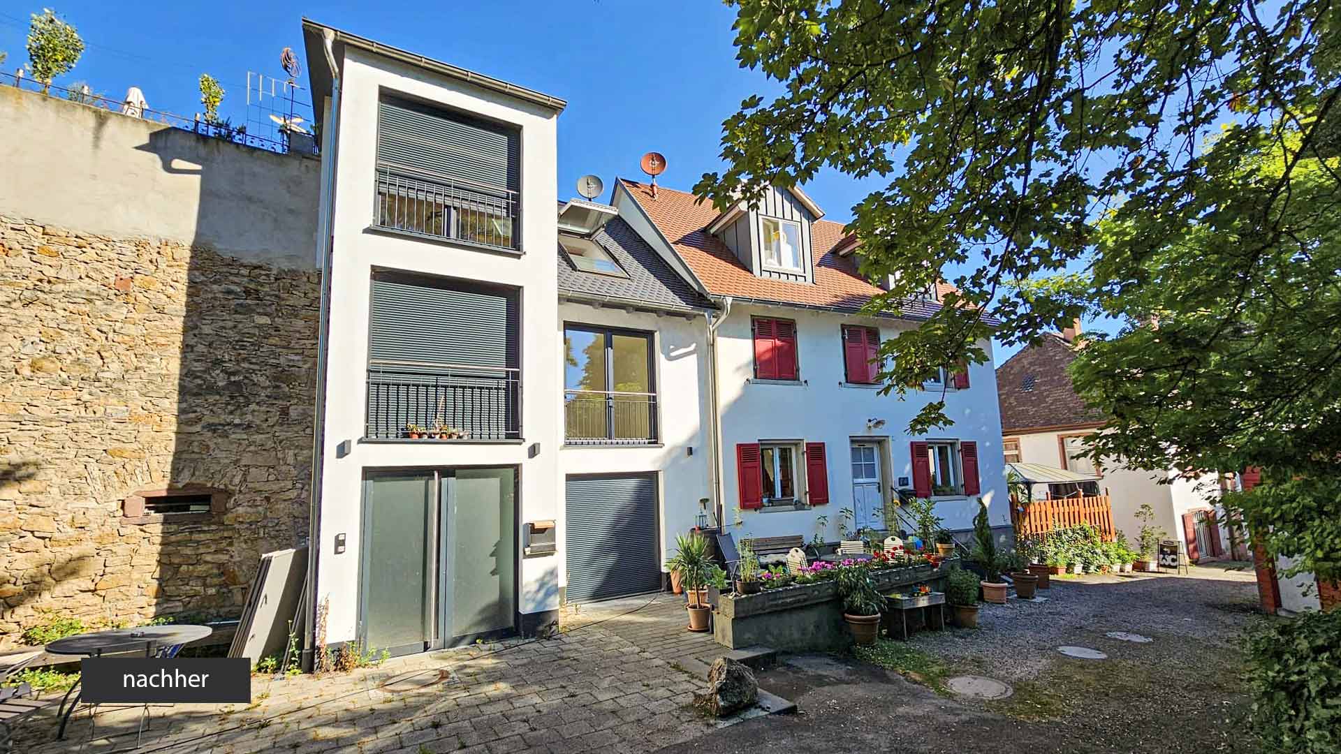 Ansicht auf ein weisses Gebäude an einer Steinmauer mit Innenhof